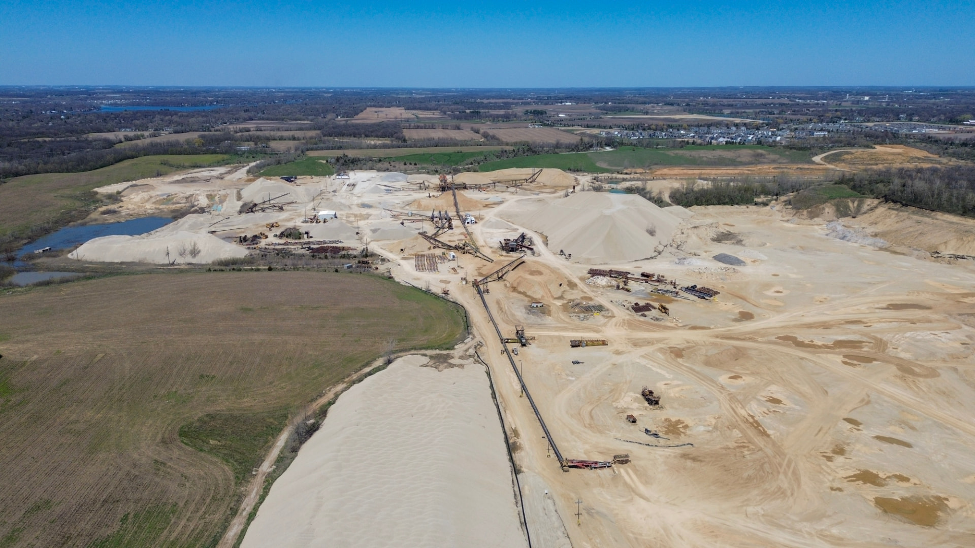 Aerial view of an undeveloped sand and gravel site with stockpiles and haul roads